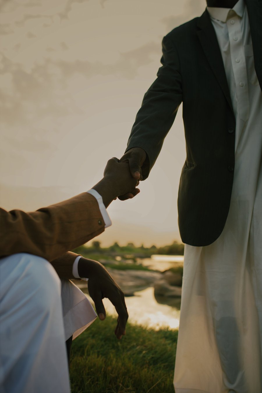 Two people shaking hands at sunset